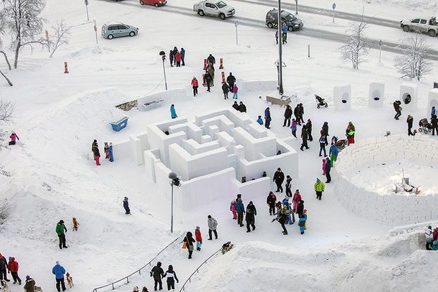 a group of people standing around a maze in the snow