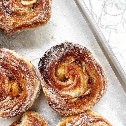 several cinnamon rolls on a baking sheet covered in powdered sugar