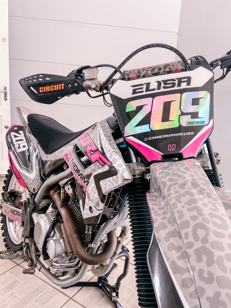 a pink and black dirt bike sitting on top of a tile floor next to a door