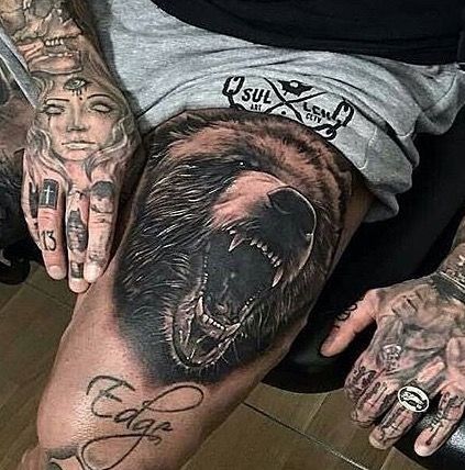 a man with tattoos on his arm and hand holding a bear's head in front of him