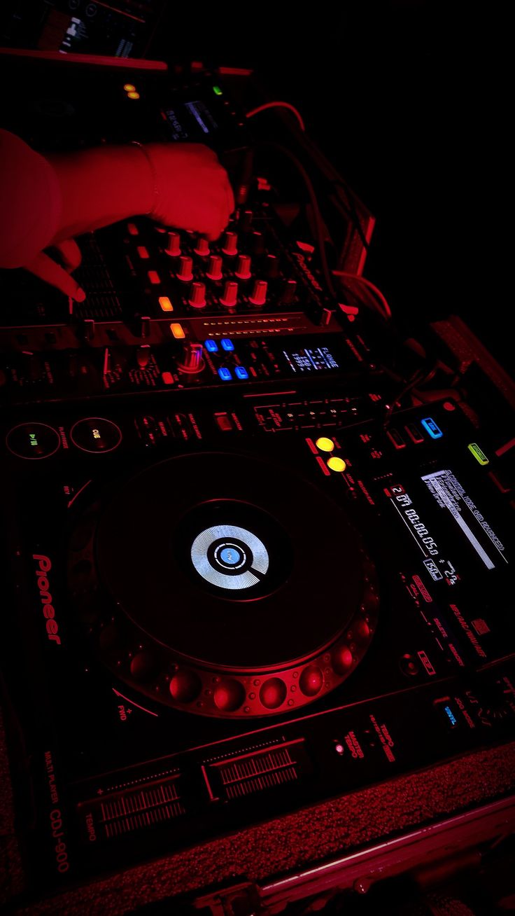 a dj mixing music in the dark with his hands on it's turntable