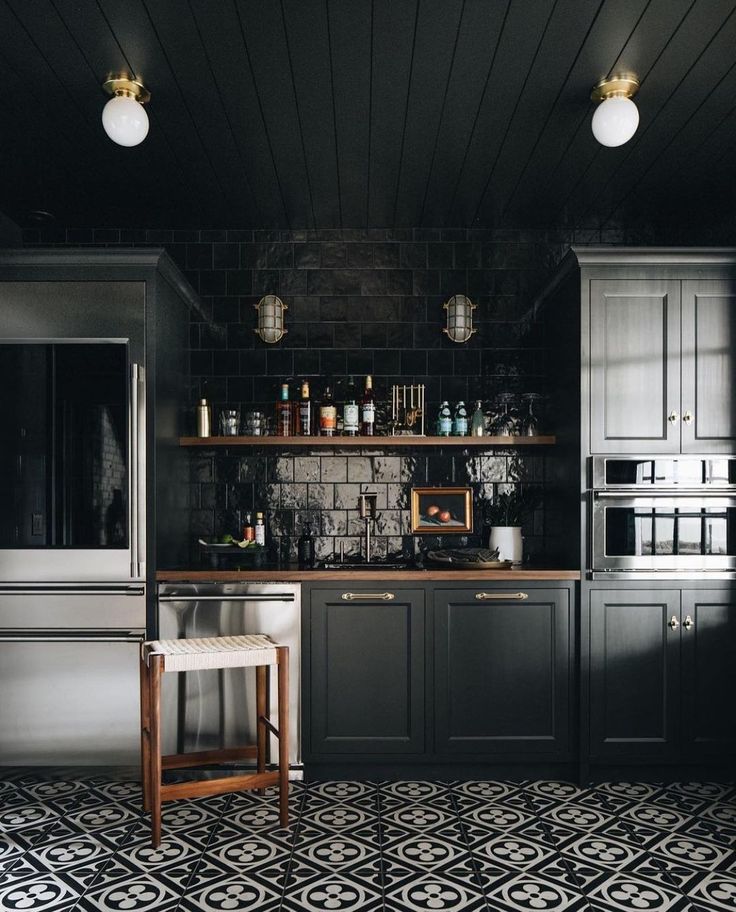 a kitchen with black and white tiles on the floor, dark cabinets and counter tops