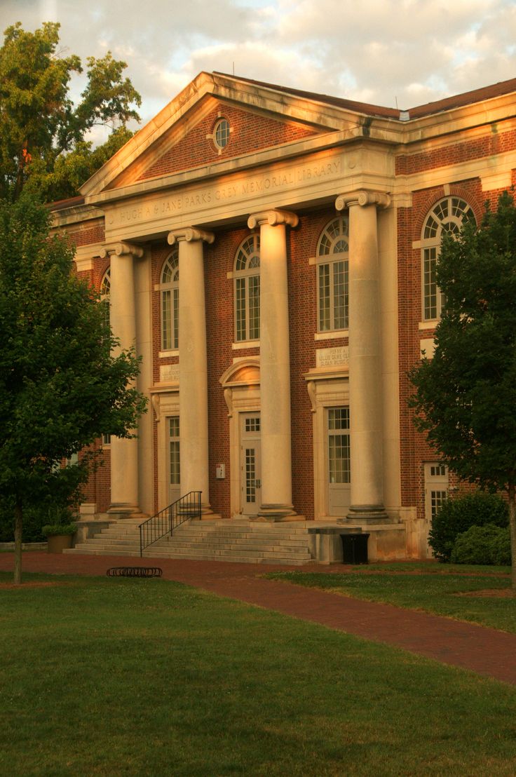 an old brick building with columns on the front and stairs leading up to it's entrance