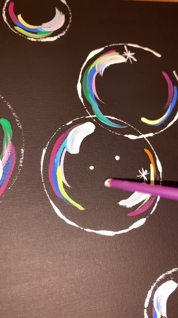 someone is drawing with colored pencils on a piece of paper that has circles and stars