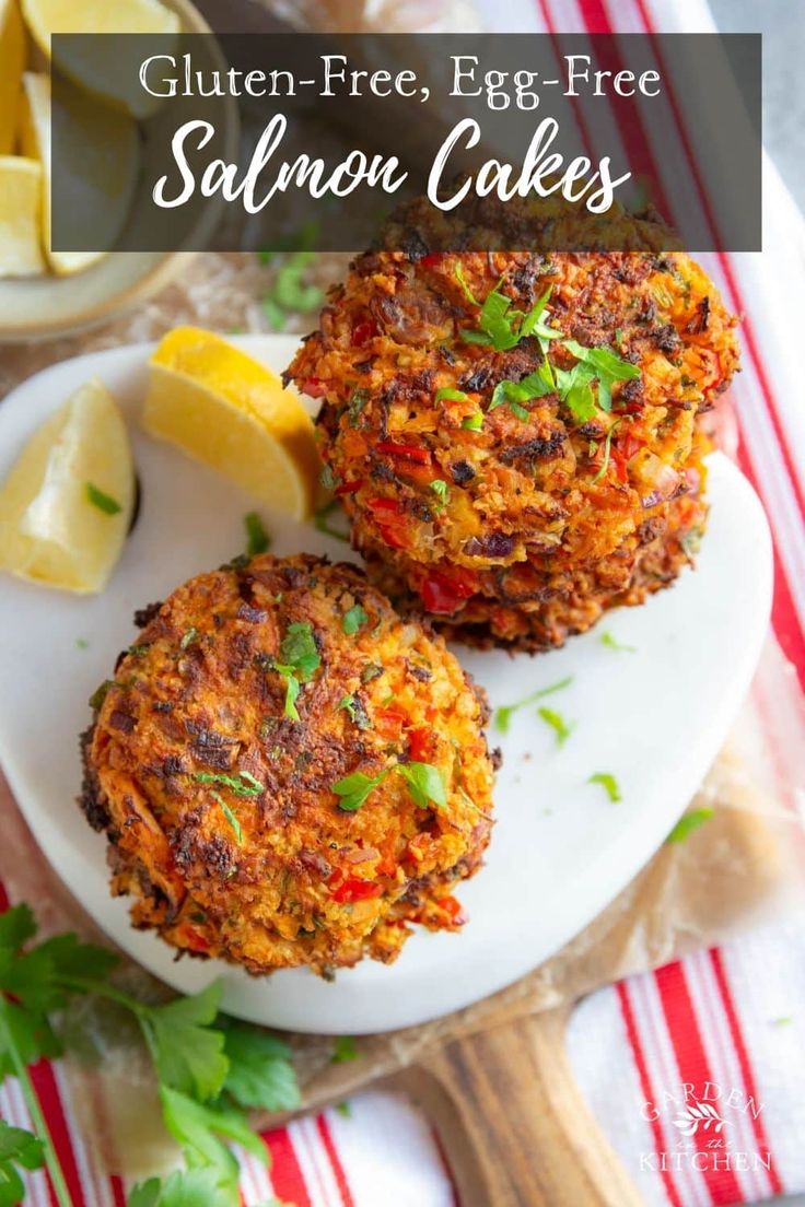 two crab cakes on a plate with lemon wedges