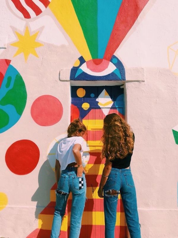 two women standing in front of a colorful wall