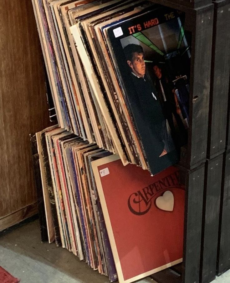 a bunch of records stacked on top of each other next to a cabinet filled with them