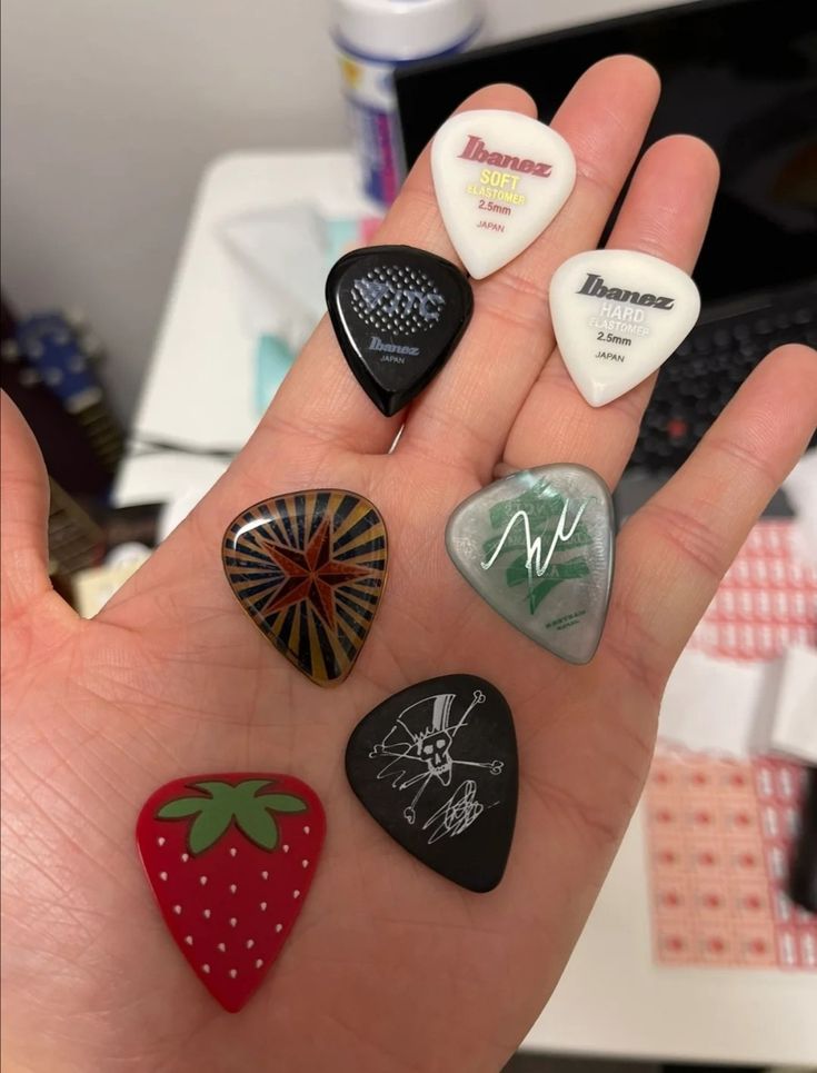 a hand holding six different colored rocks in it's palm with writing on them