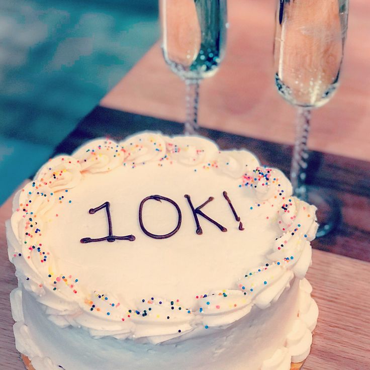 a cake with the word 10k on it and two glasses of champagne behind it