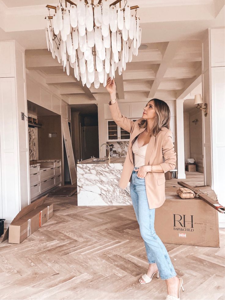 a woman standing next to a chandelier in a living room