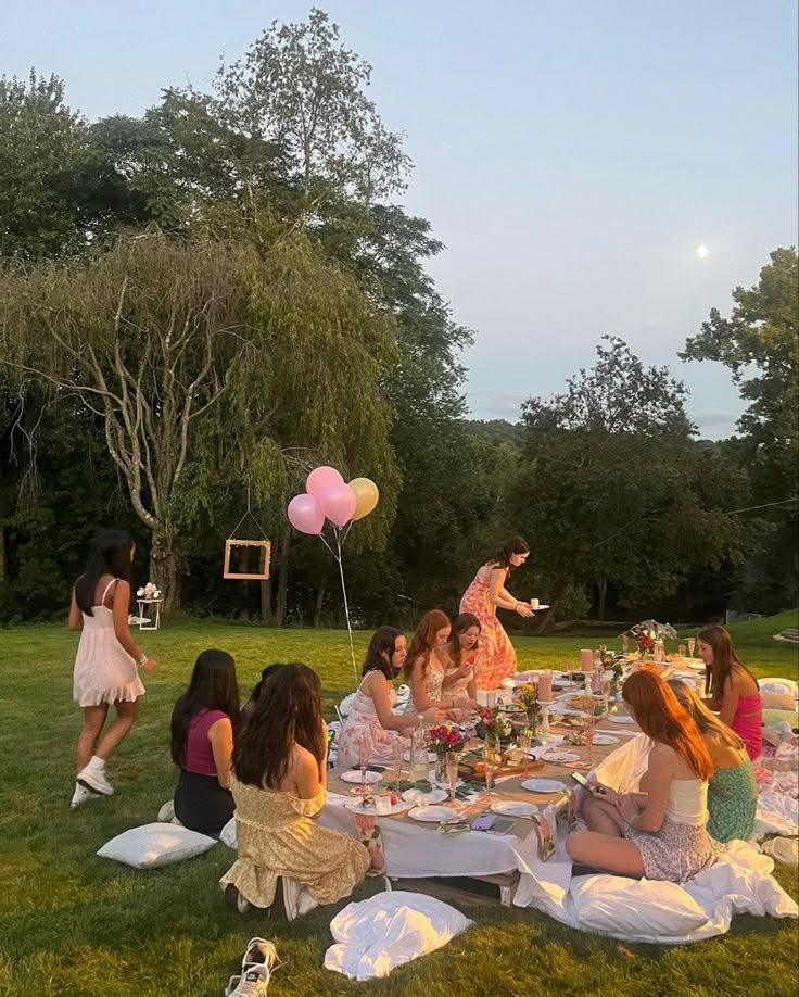 a group of women sitting around a table with pink balloons in the shape of heart