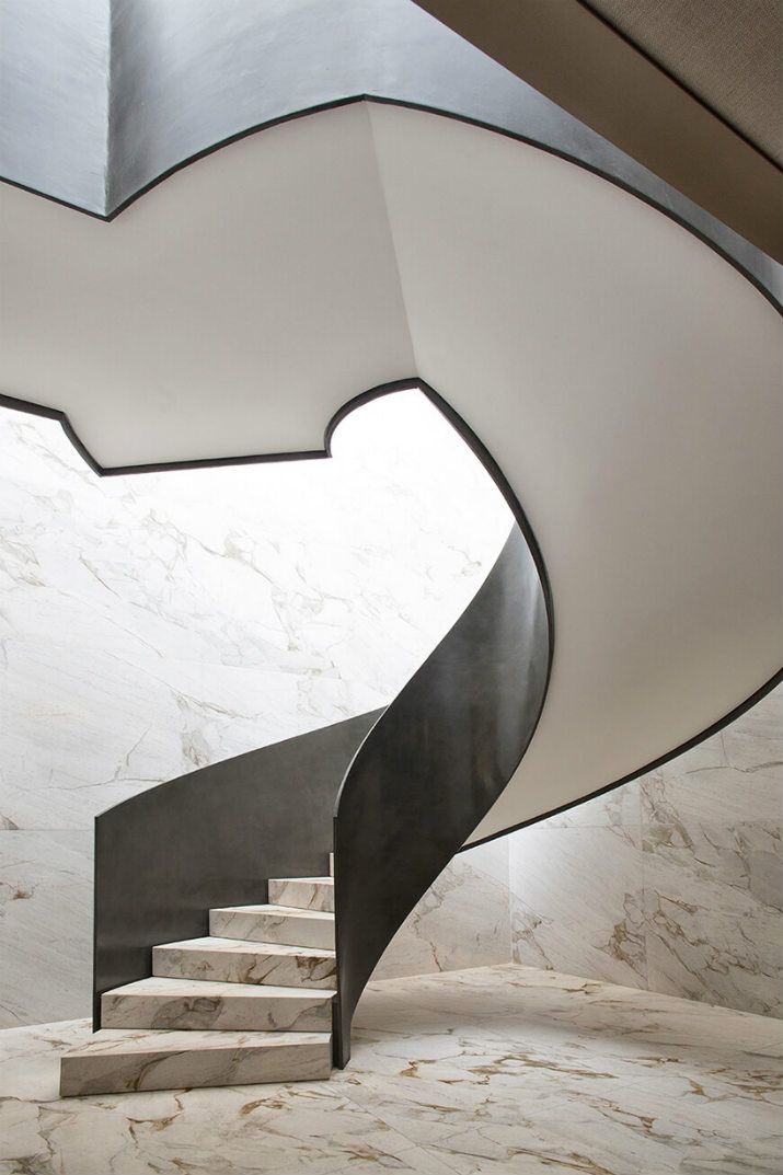 a spiral staircase with marble floors and walls