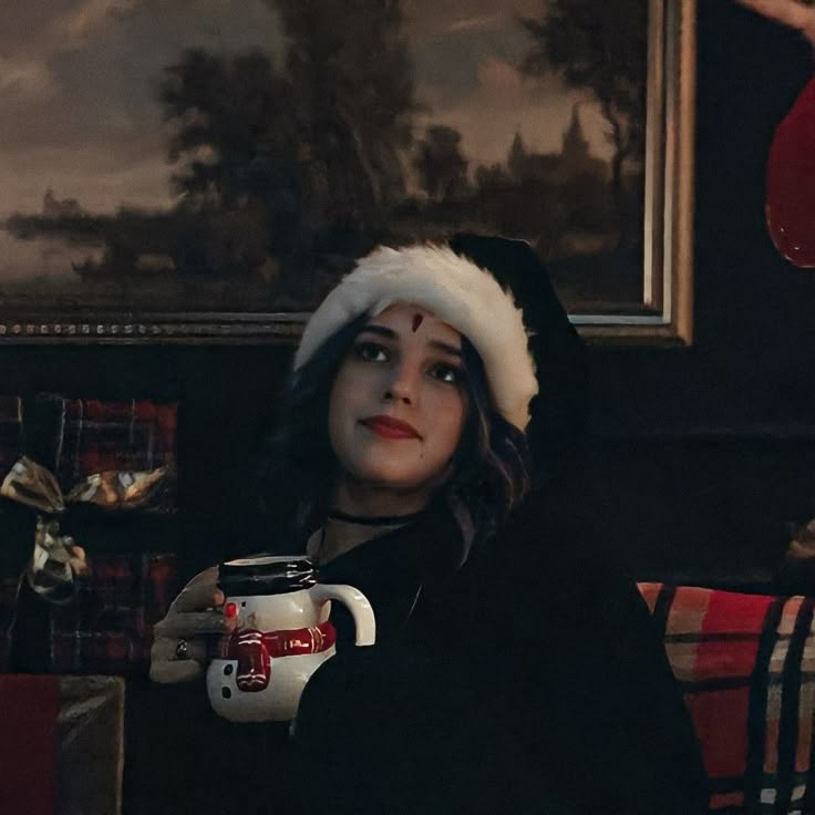 a woman wearing a santa hat holding a mug