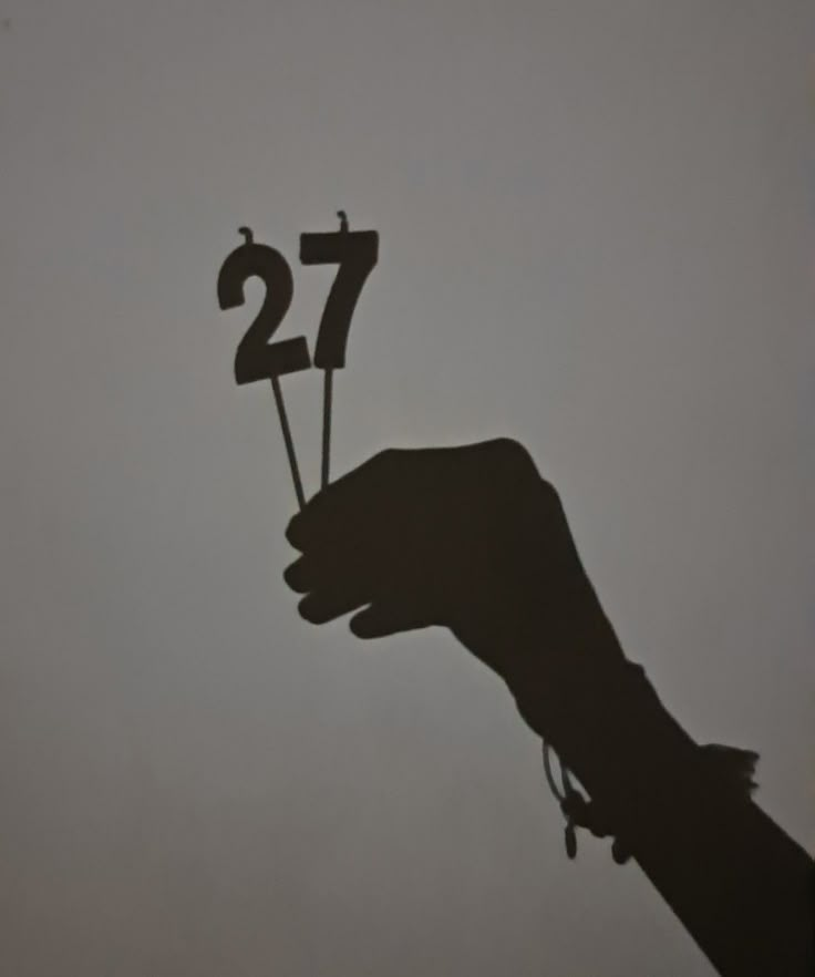 a hand holding a small black sign with the number twenty seven on it