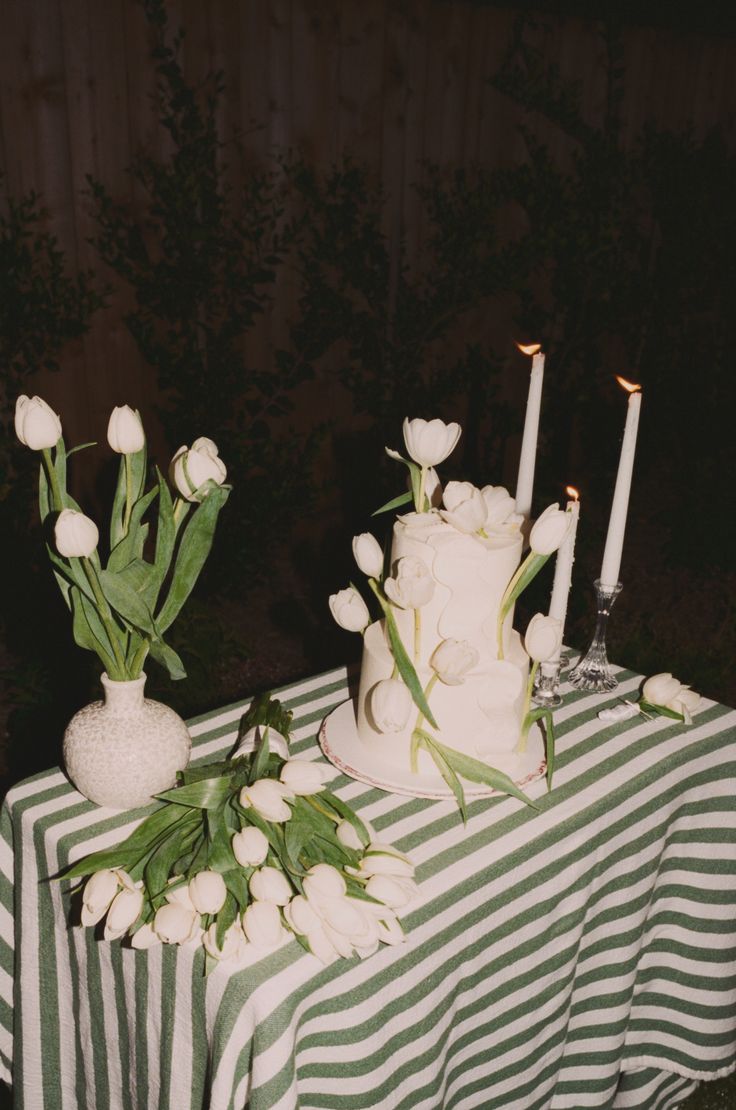 a table topped with a white cake and flowers