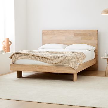 a bed sitting on top of a wooden floor next to a white rug in a bedroom