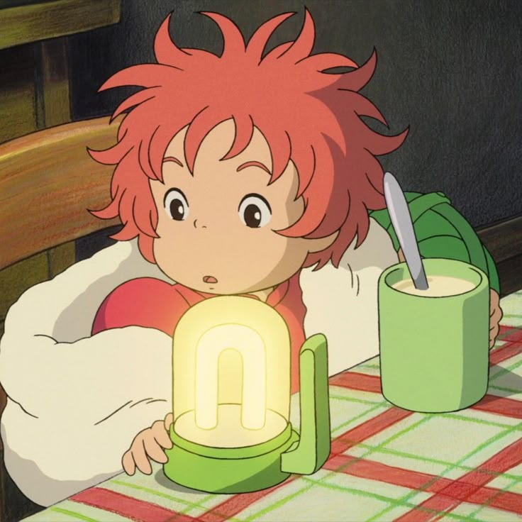 a young boy sitting at a table with a light in front of him and a mug on the table