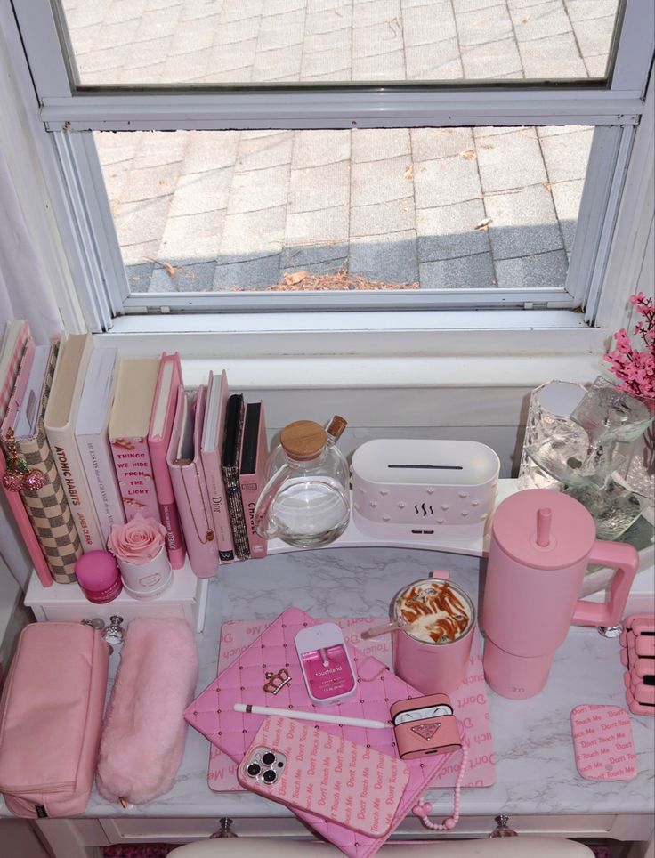 a vanity with pink accessories on it next to a window