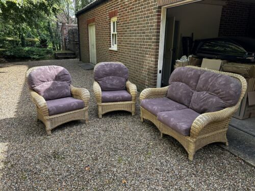 three wicker chairs sitting next to each other in front of a brick wall and garage