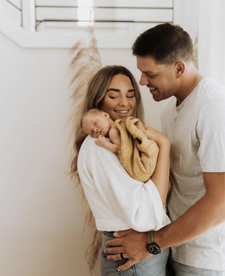 a man and woman holding a baby in their arms