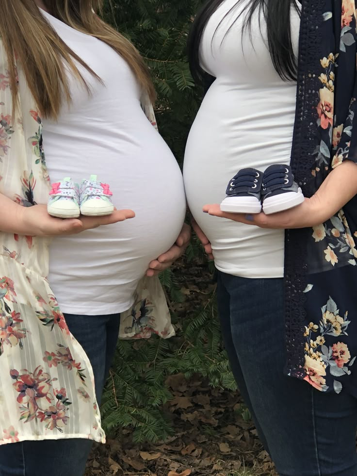 two pregnant women holding their baby shoes