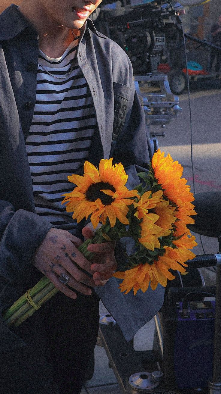 a young man holding a bouquet of sunflowers