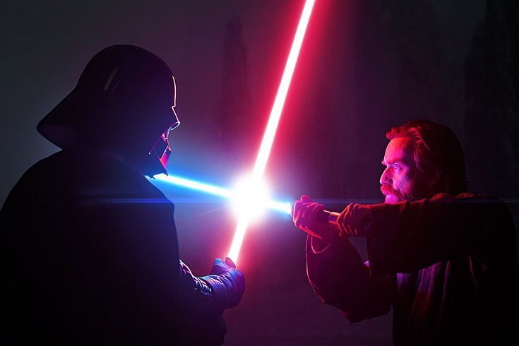 two people with lightsabens in the dark, one is holding a light saber