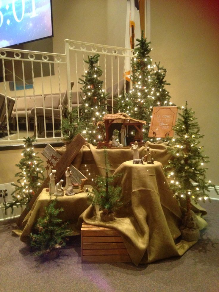 christmas trees with lights and decorations on display in front of a television screen at the bottom of stairs