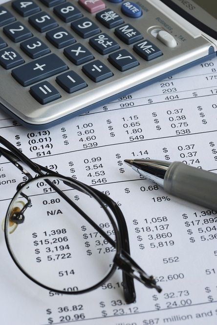 a calculator, glasses and pen on top of a spreadsheet with numbers