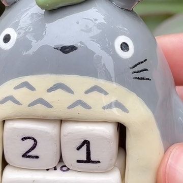 a close up of a ceramic figurine of a totoro with its mouth open