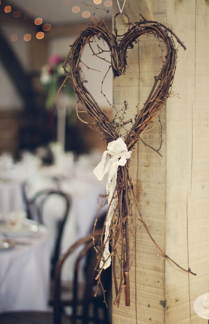 a heart shaped decoration hanging from the side of a wooden post at a wedding reception