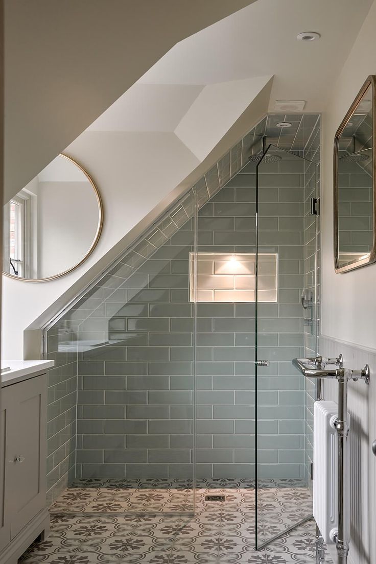 a bathroom with a glass shower door and tiled floor, along with two mirrors on the wall