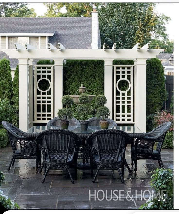 an outdoor dining area with chairs and table in front of a pergolated wall