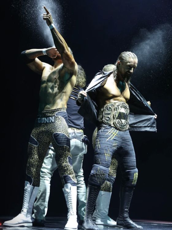 two men are performing on stage with their arms in the air and one man is holding his hands up