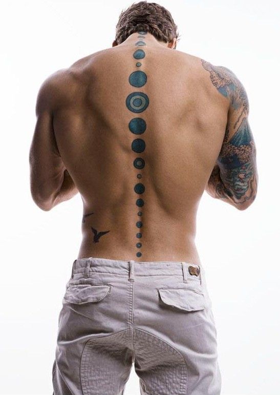 a man with his back turned to the camera and tattoos on his upper half, looking down