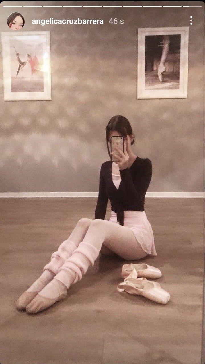 a woman sitting on the floor talking on her cell phone with ballet shoes in front of her