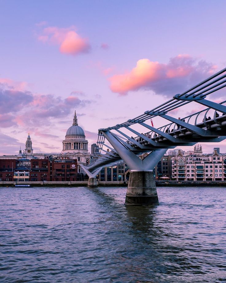 an image of a bridge going over the water with buildings in the background at sunset