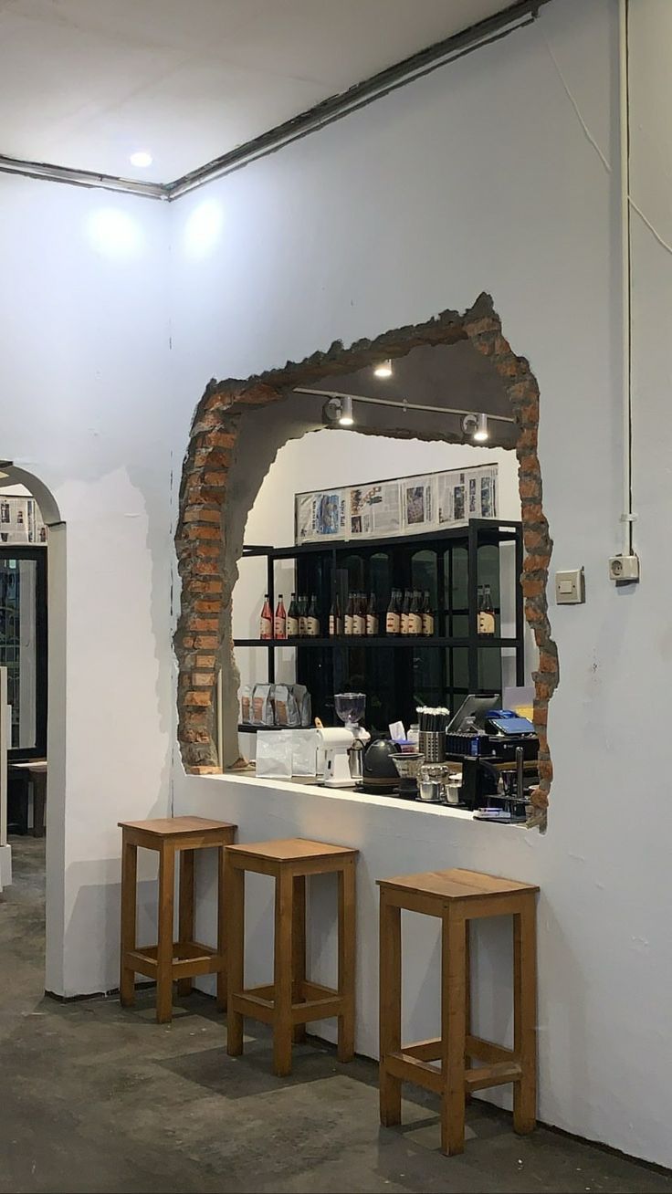 two wooden stools sitting in front of a counter with a mirror on the wall