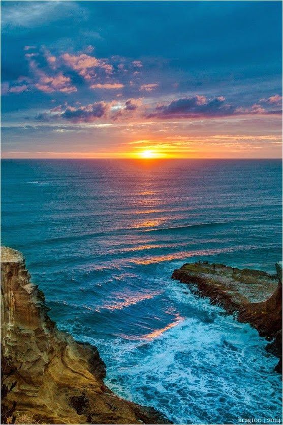 the sun is setting over the ocean and rocks