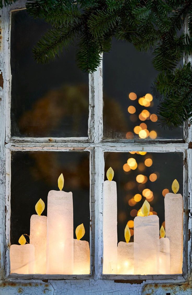 candles are lit in front of a window