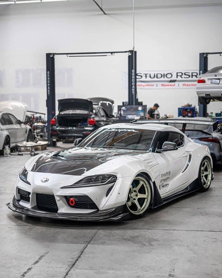 a white sports car parked in a garage next to other cars