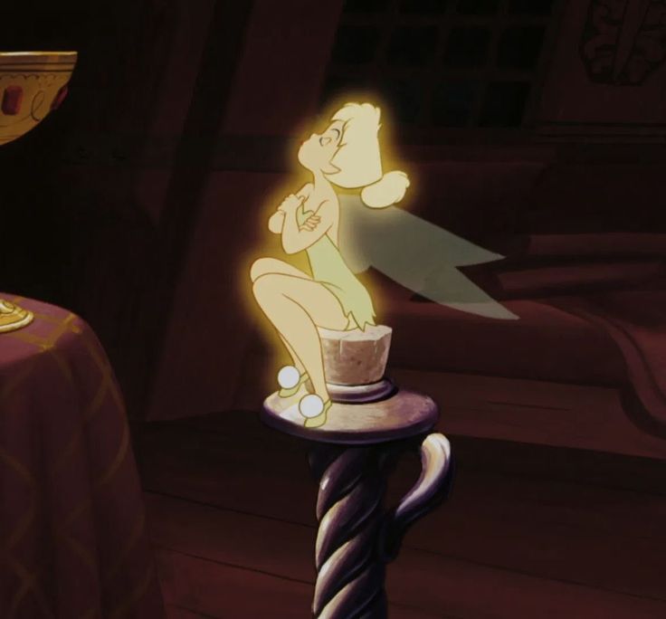 a cartoon character sitting on top of a table next to a cup and candle holder