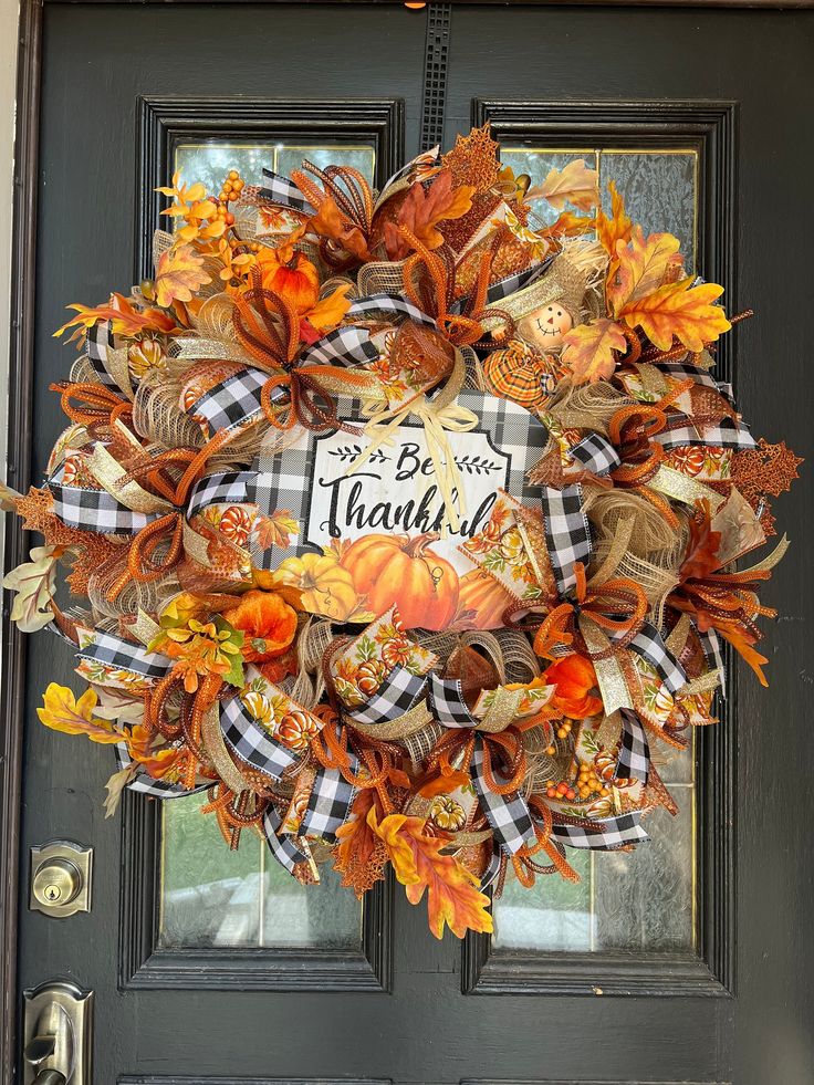 a wreath that says be grateful on it in front of a door with pumpkins and leaves