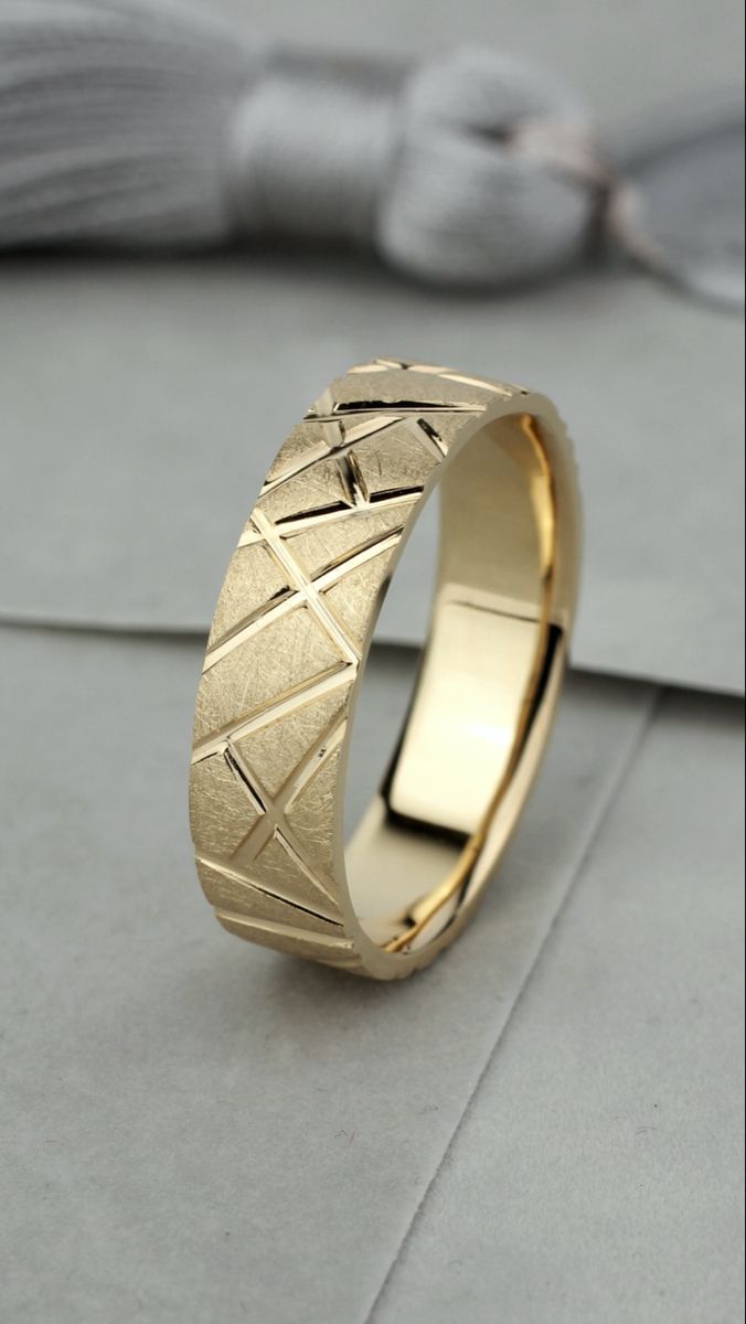 a gold wedding band with an intricate design