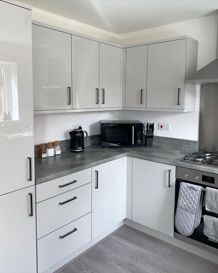 a kitchen with white cabinets and gray counter tops