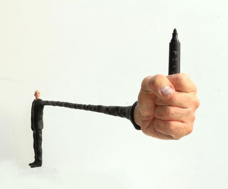 a hand holding a small black object in it's right hand and pointing at the camera