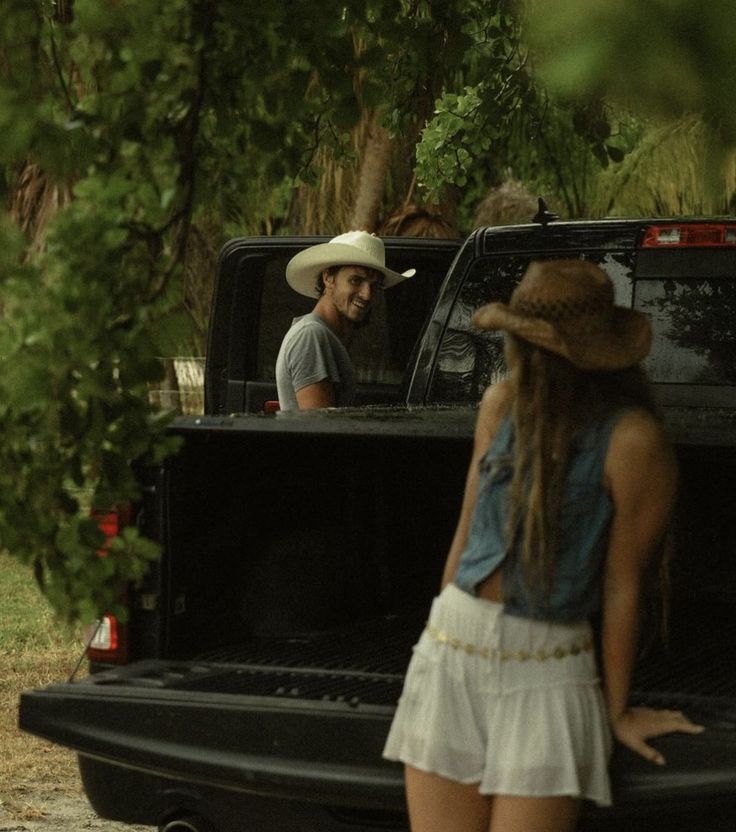 a man and woman standing in the back of a truck