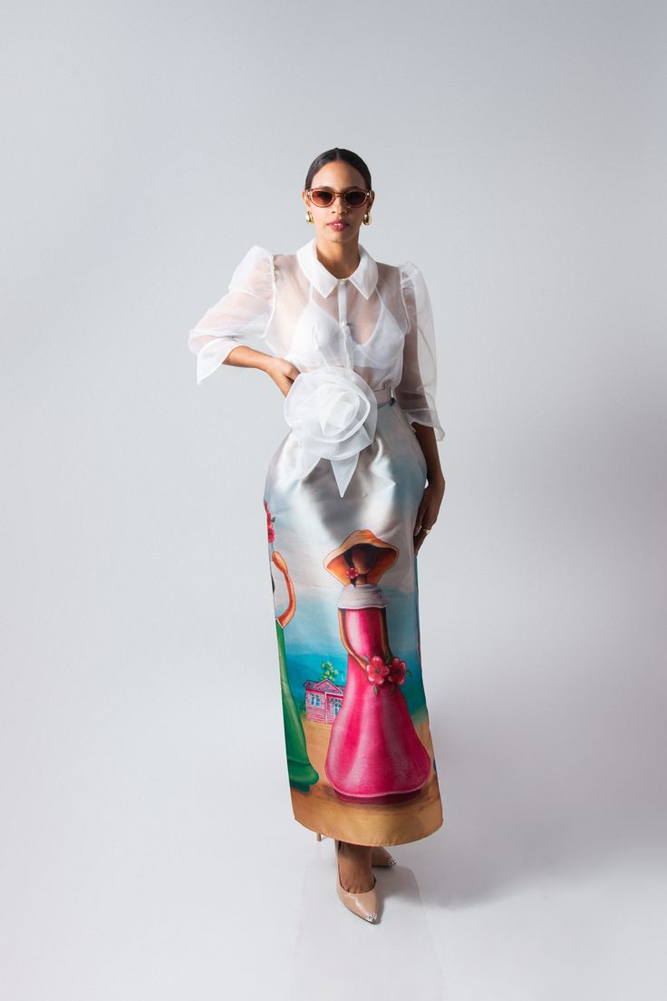 Flor de Caribe is a stunning long skirt crafted from luxurious mikado fabric, known for its rich texture and subtle sheen. The skirt features a full and graceful A-line silhouette, draping elegantly from the waist to the floor. Its standout detail is inspired by the traditional faceless dolls of the Dominican Republic. The artwork depicts these iconic figures, symbolizing Dominican heritage and culture, with soft, flowing lines and vibrant colors that stand out against the smooth surface of the Dominican Faceless Dolls, Elegant Floor-length Satin Skirt, Chic Silk Full Maxi Skirt, Spring Evening Silk Maxi Skirt, Spring Evening Silk Skirt, Silk Evening Skirt For Spring, Chic Silk Voluminous Maxi Skirt, Luxury Silk Skirt For Spring, Chic Voluminous Silk Maxi Skirt