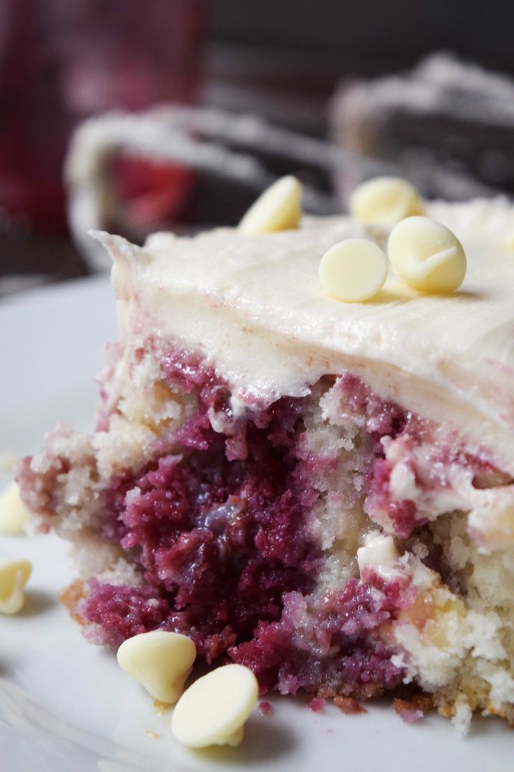 a close up of a piece of cake on a plate with white frosting and chocolate chips