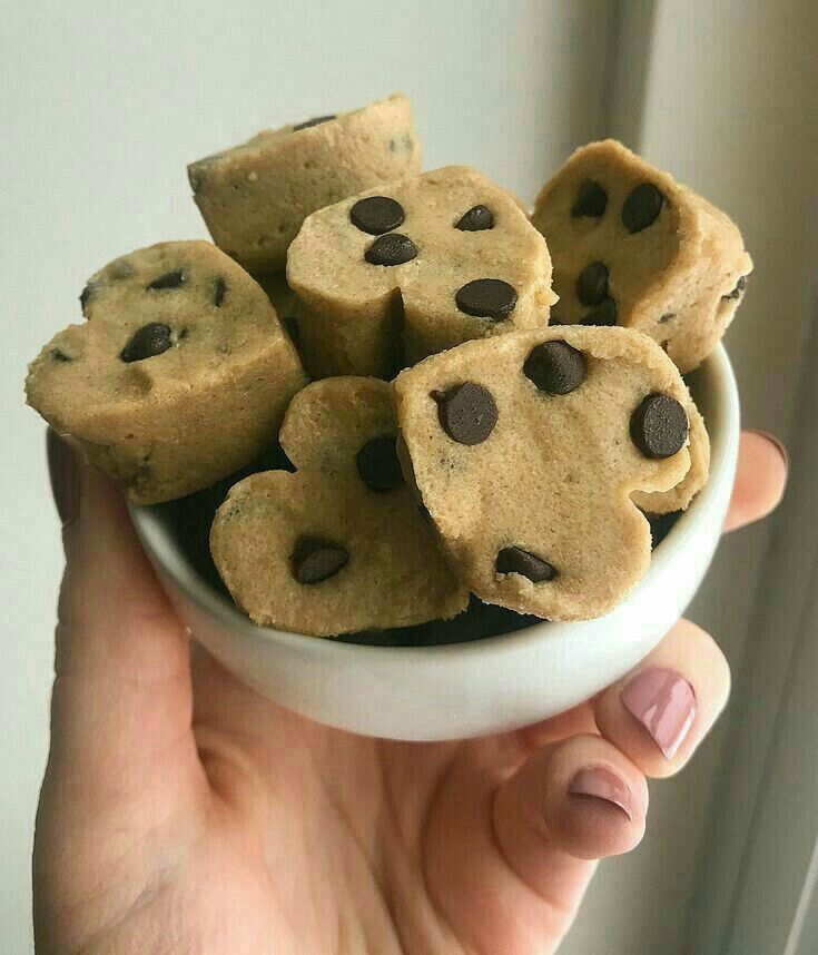 a person holding a bowl filled with chocolate chip cookies